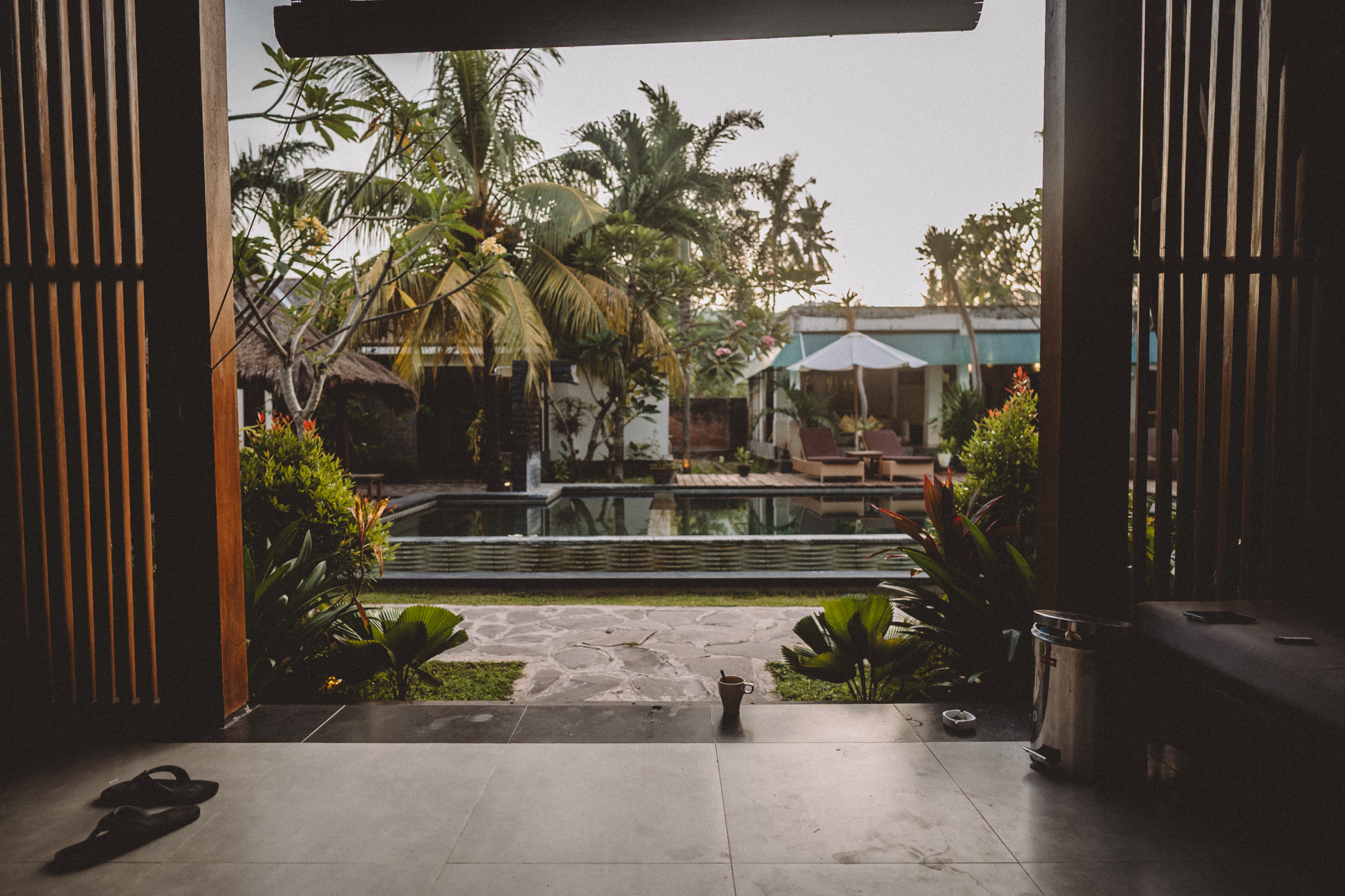Open wooden doors framing a quiet pool and palms in Lombok