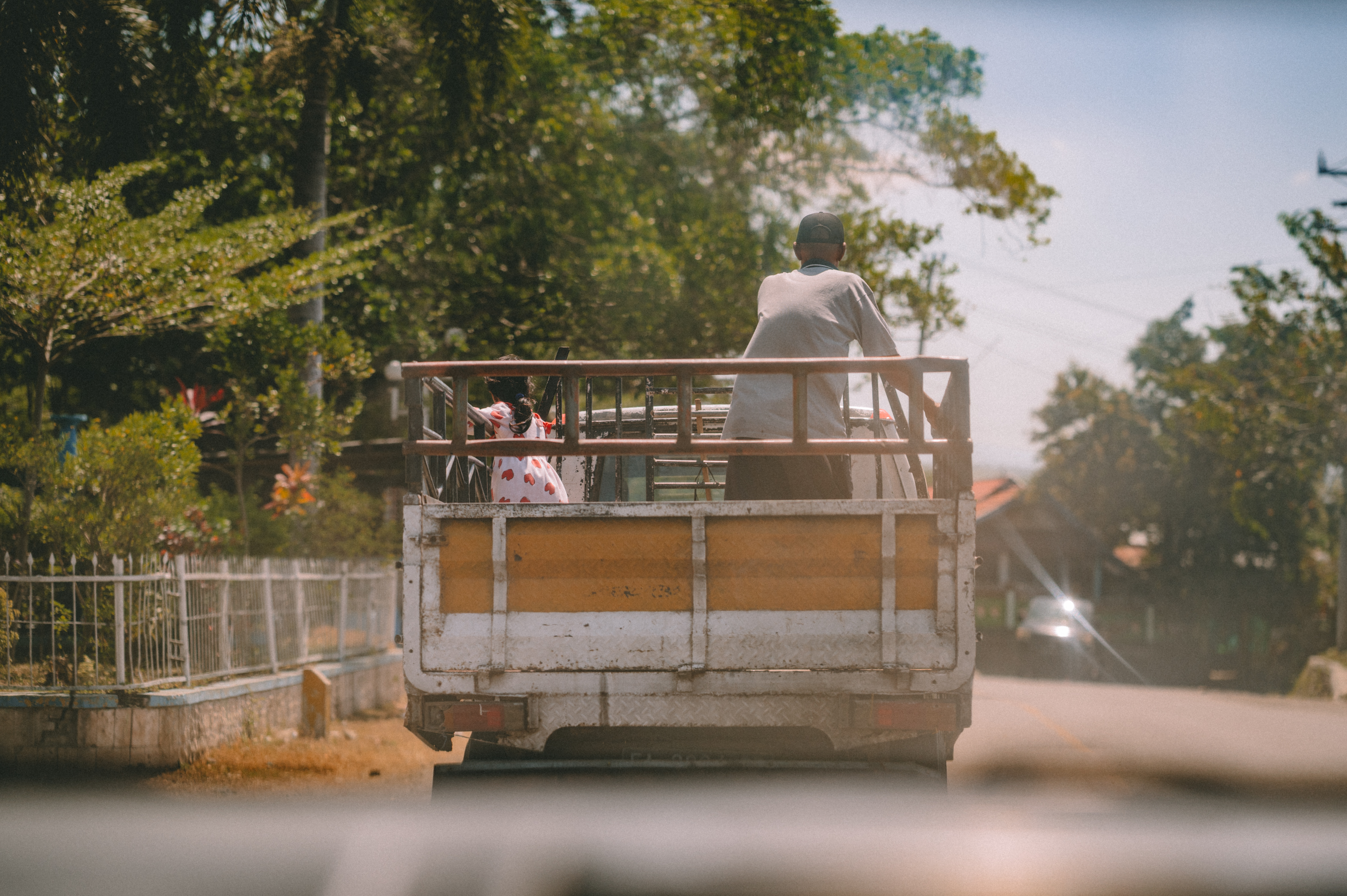 A passenger riding in the back of a small truck