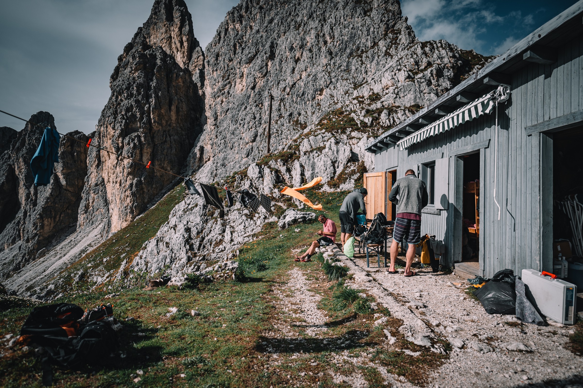 Bergsteiger vor einer kleinen Hütte am Fuß einer Felswand