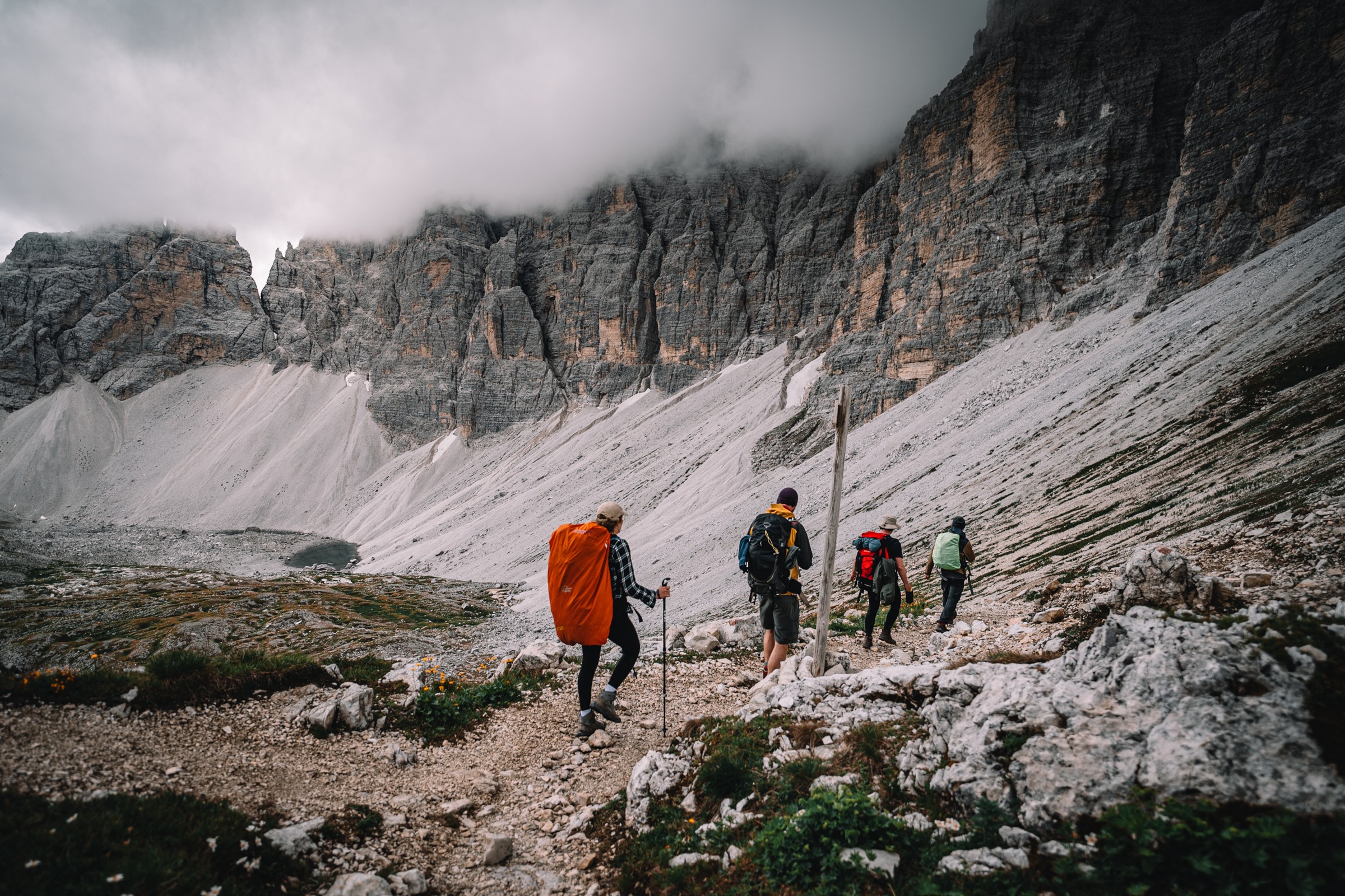 Wandergruppe auf einem Pfad unter wolkenverhangenen Felswänden