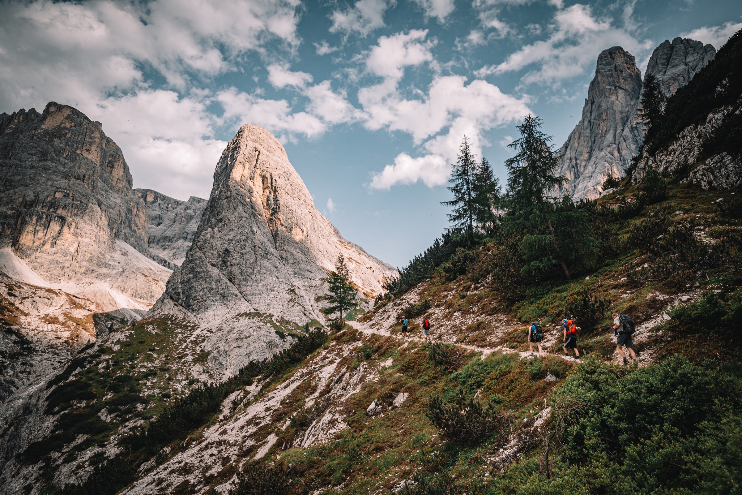 Bergpfad mit kleinen Wanderern unter einer markanten Felsspitze