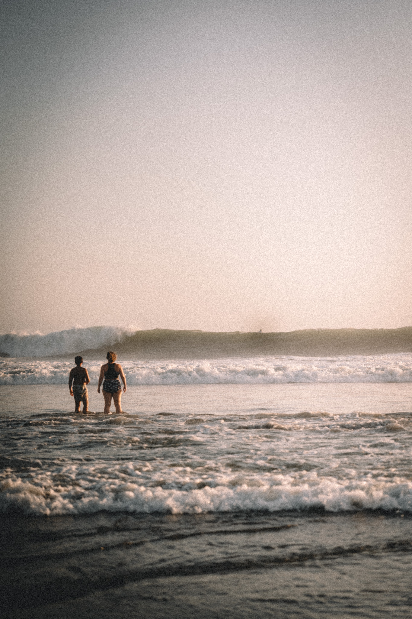 Two people standing in the evening surf