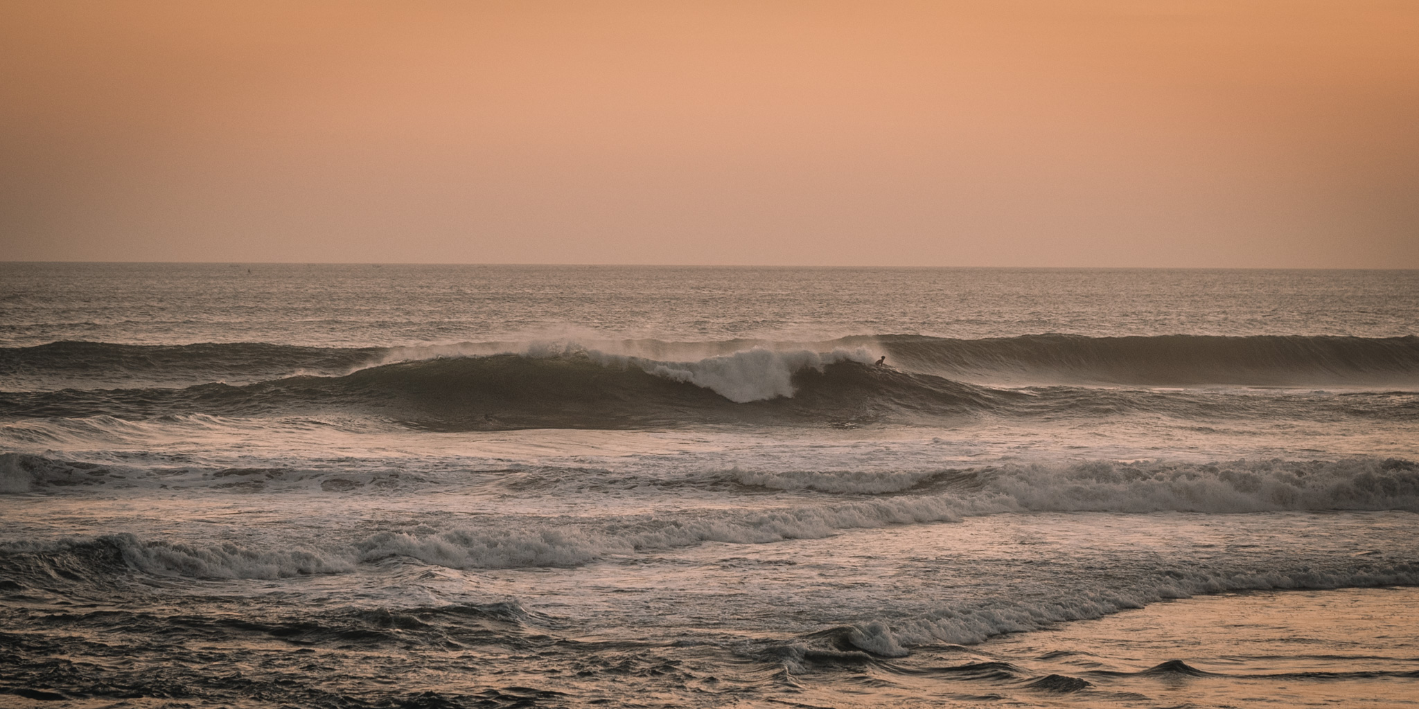 Waves beneath a warm sunset sky