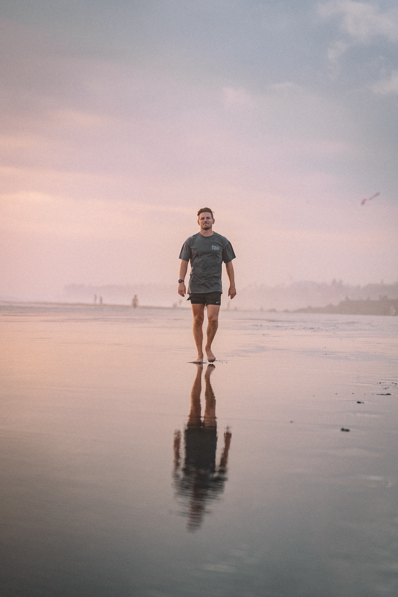 A person reflected in wet sand at dusk