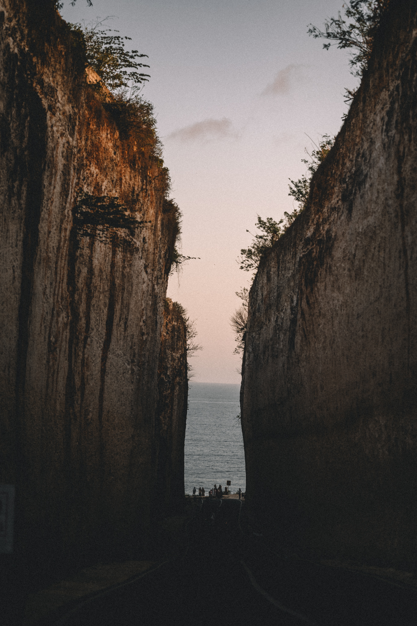 A narrow passage between cliffs opening onto the sea at dusk