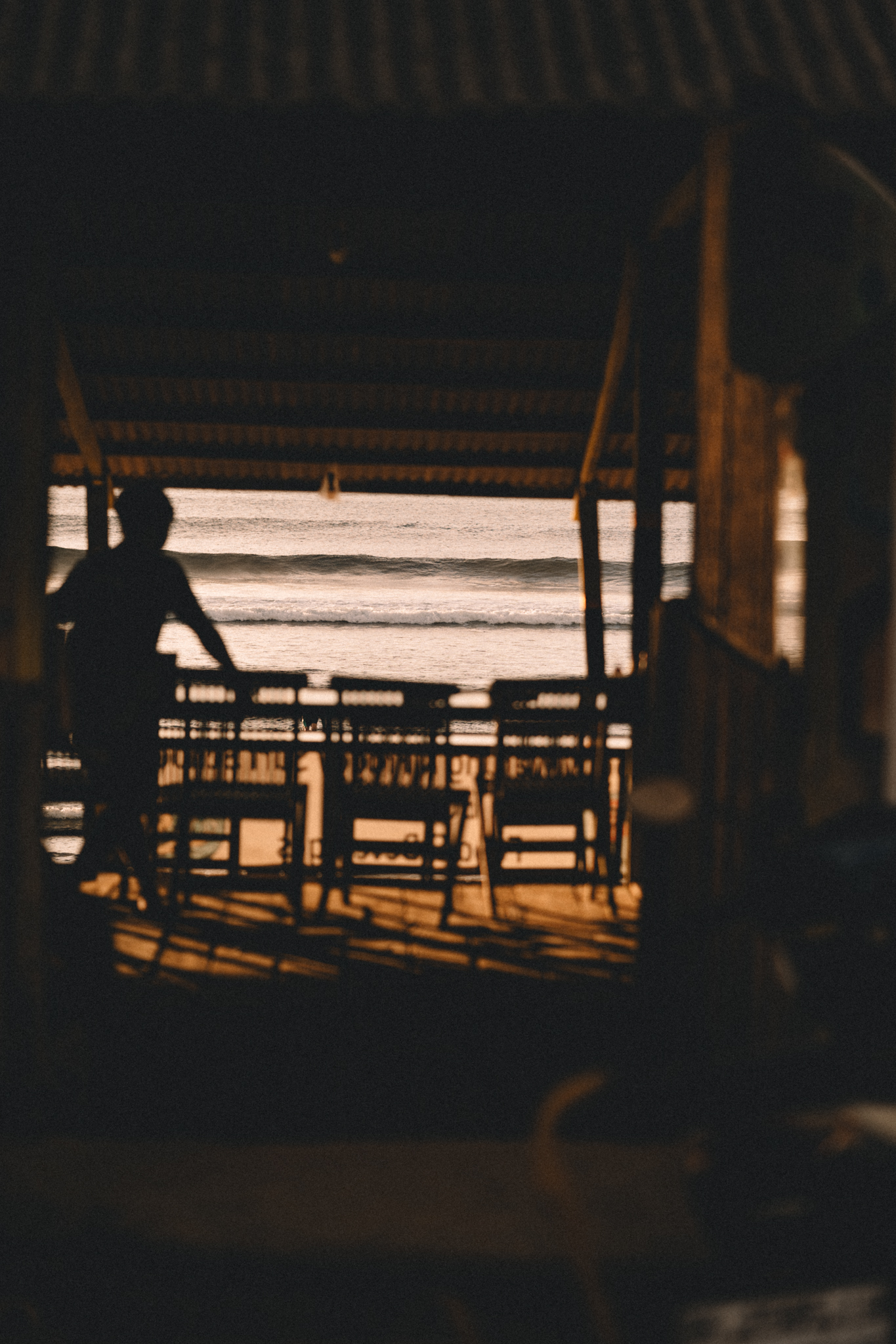 A quiet silhouette inside a beachside shelter at sunset