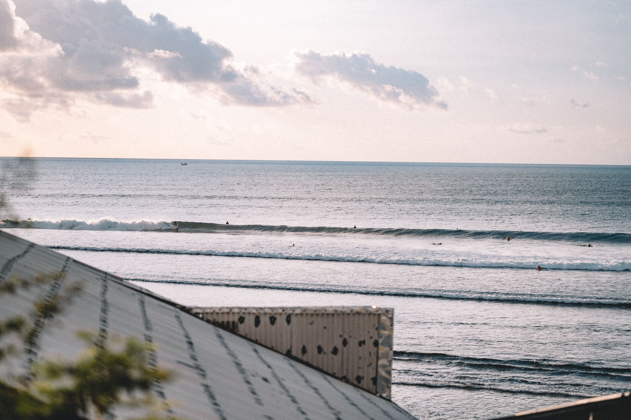 A quiet coastline with lines of surf under pale clouds