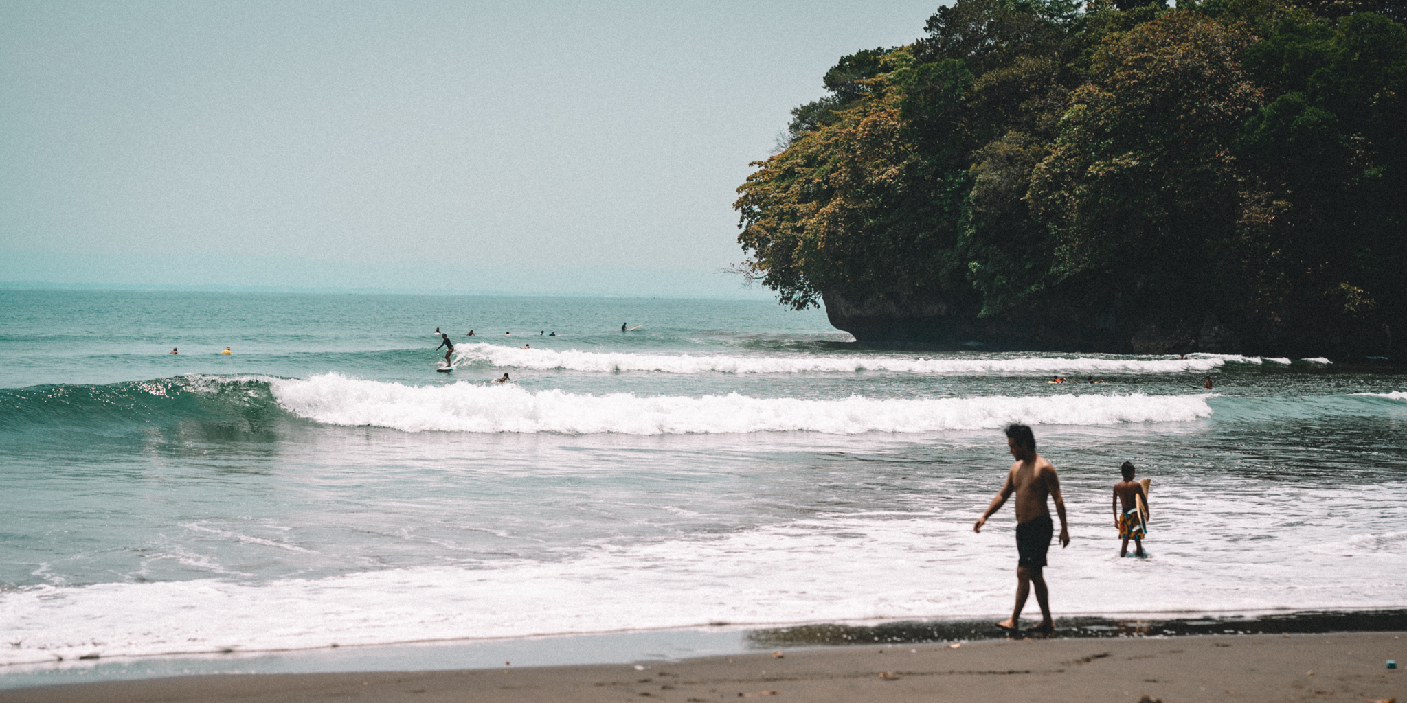 A surfer and another person by a quiet turquoise shore