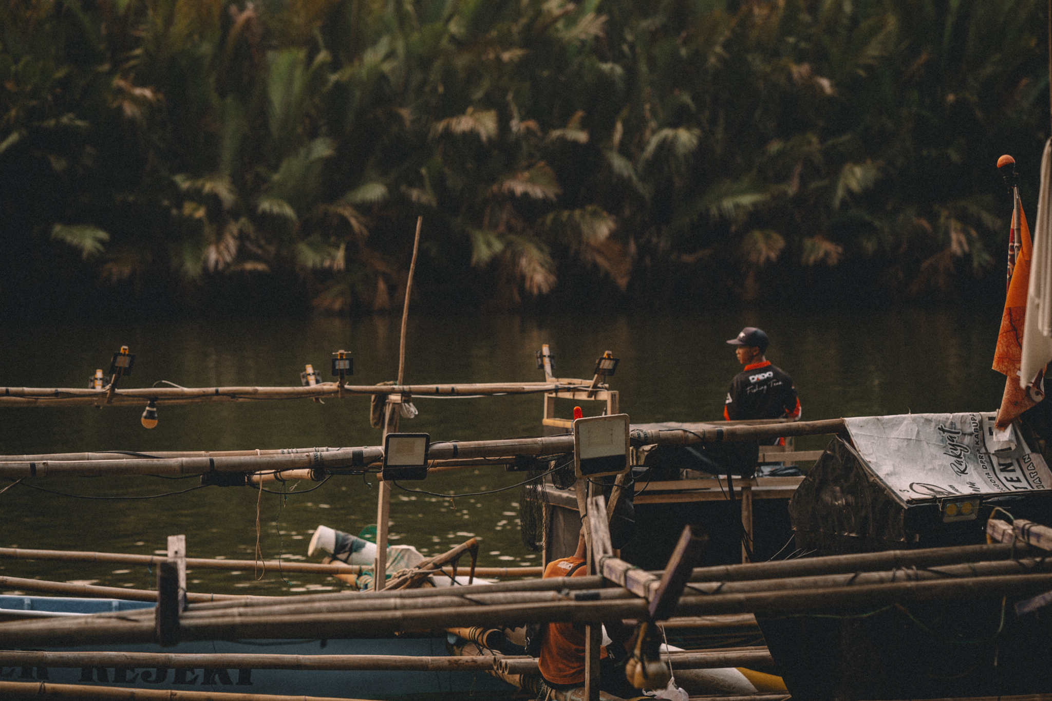 Fishing boats and people beside a lush riverbank