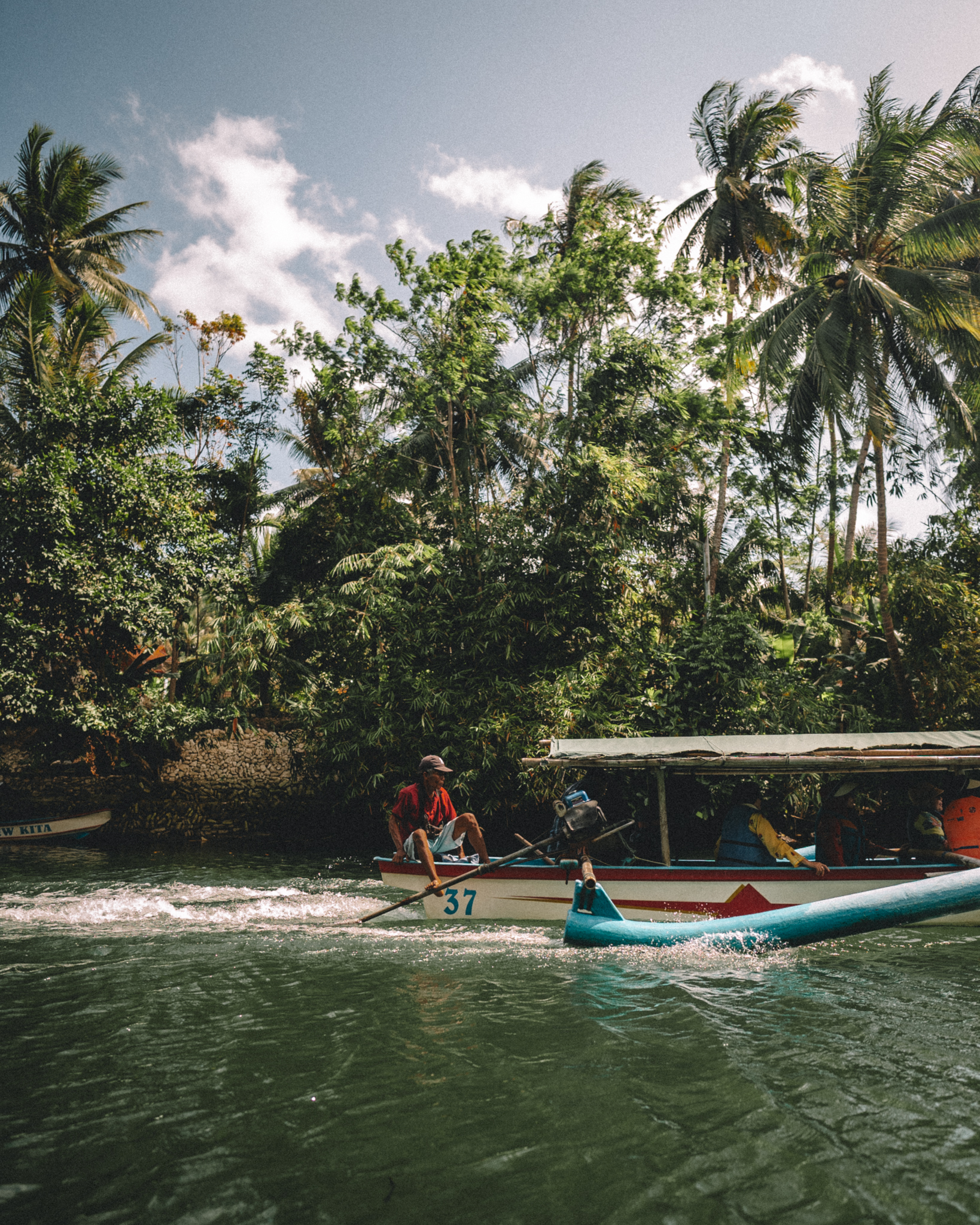 People travelling by small boat along a lush shore