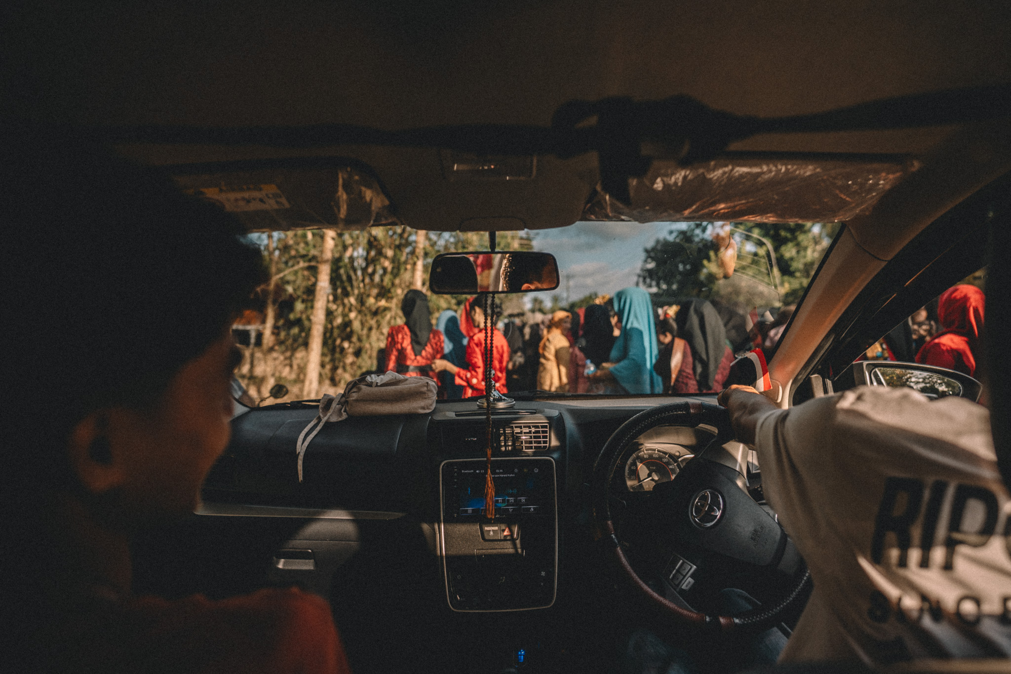 A street procession seen through a vehicle windscreen