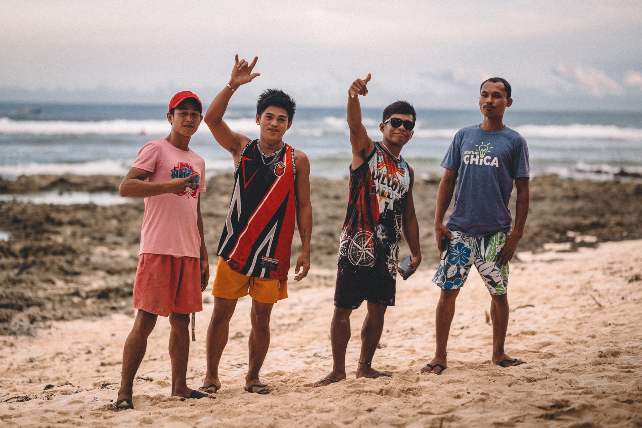 Four friends greeting the camera on the beach