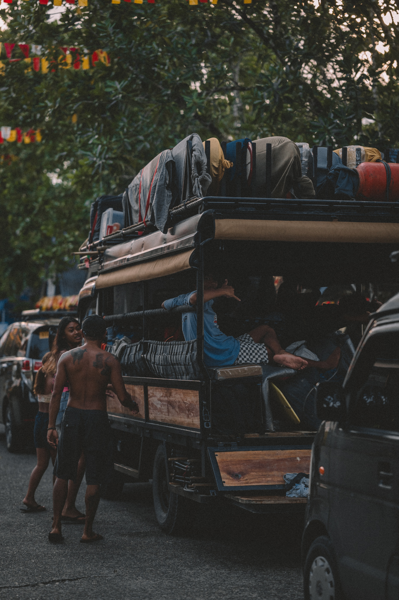 A crowded vehicle carrying luggage through town