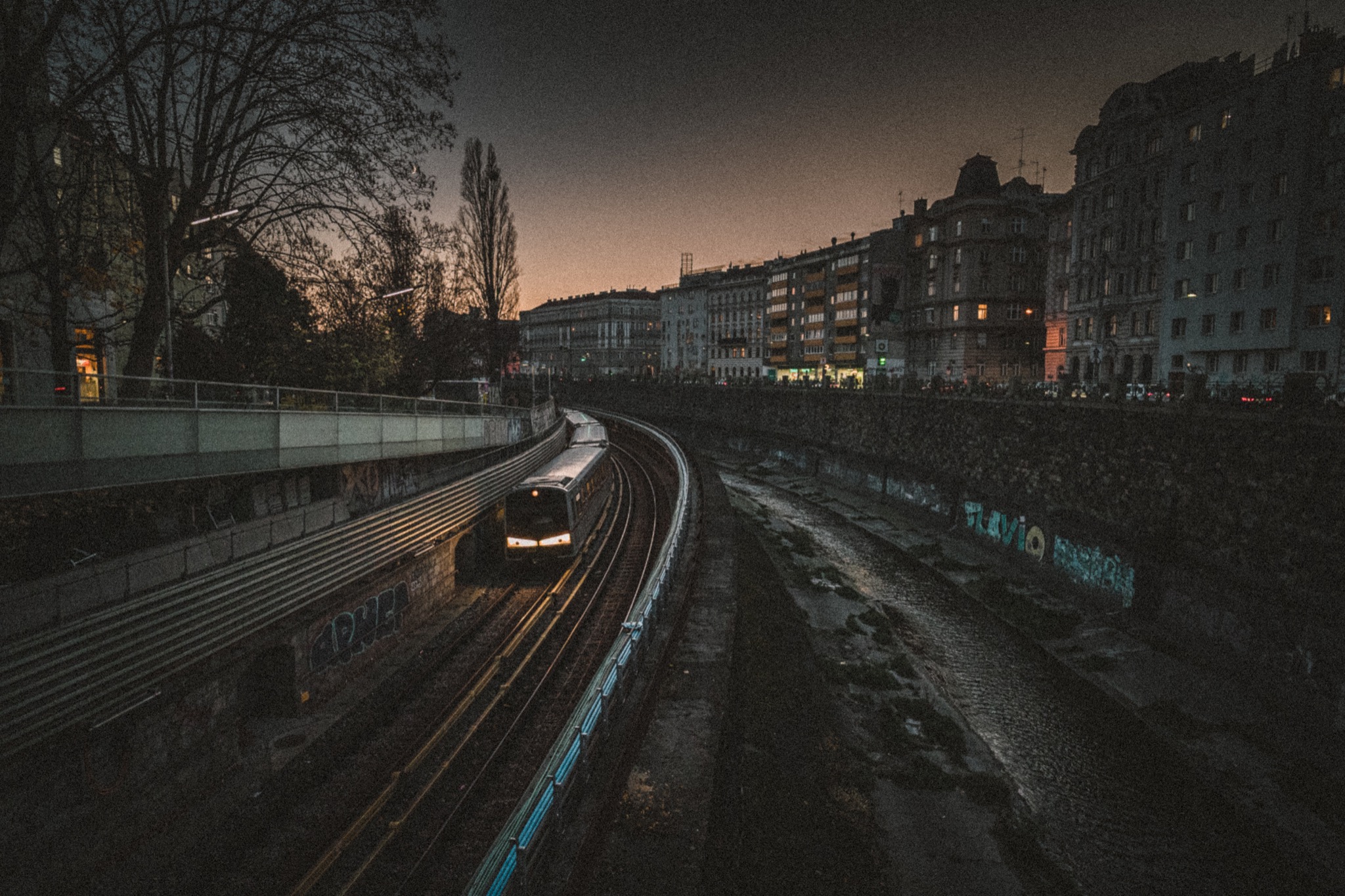 Eine U-Bahn fährt bei Dämmerung zwischen Wiener Häusern