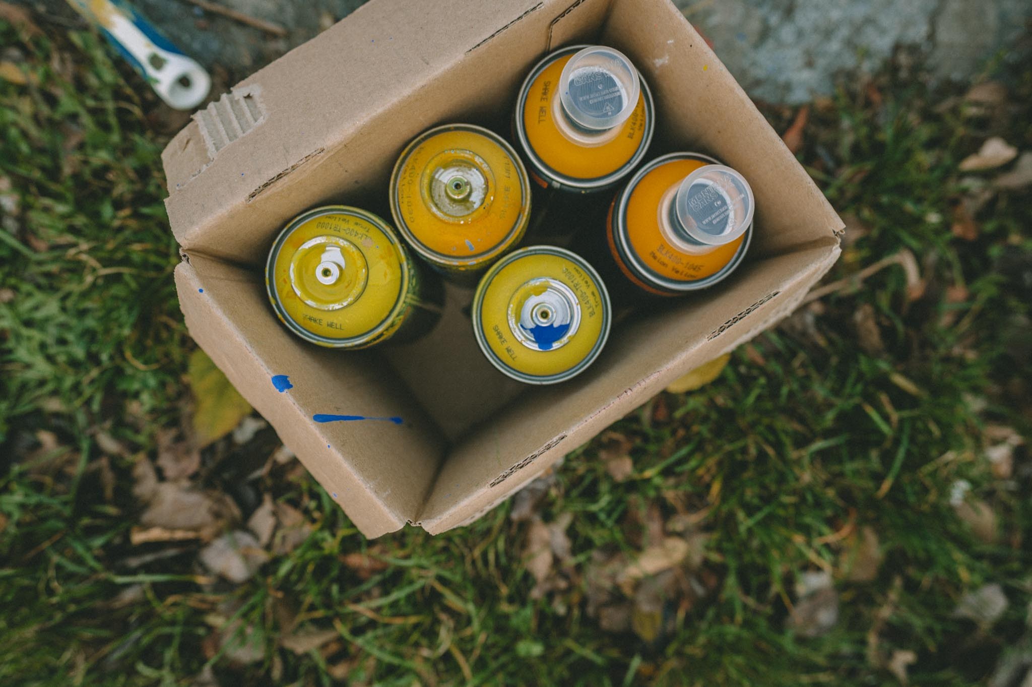 Gelbe Spraydosen in einem Karton, von oben fotografiert
