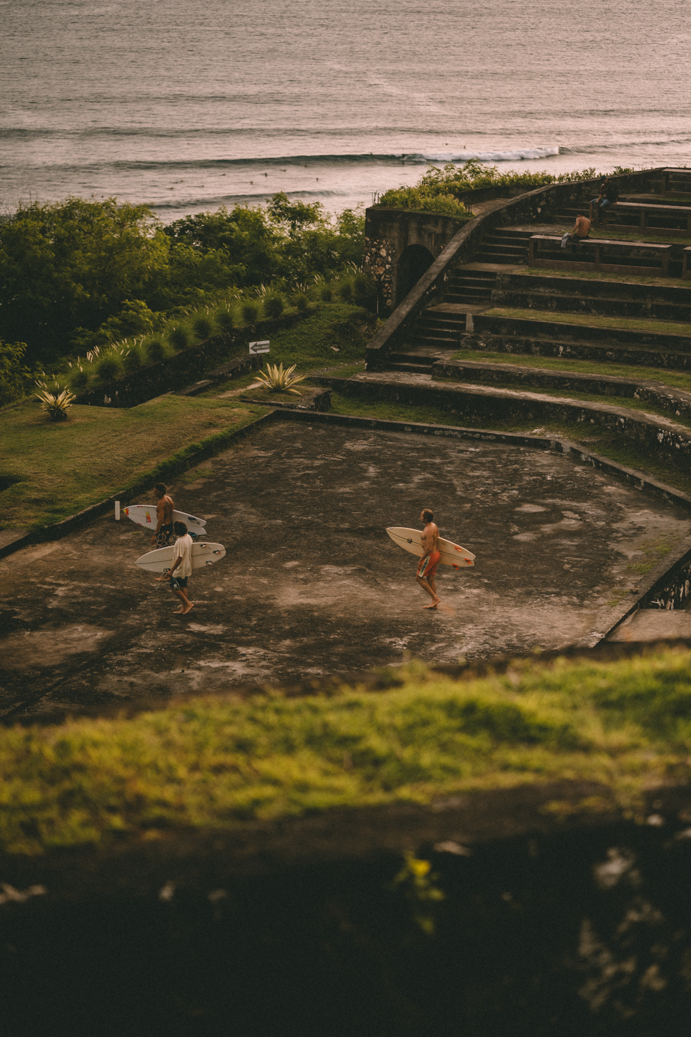 Surfers carrying their boards through curved seaside steps in Bali