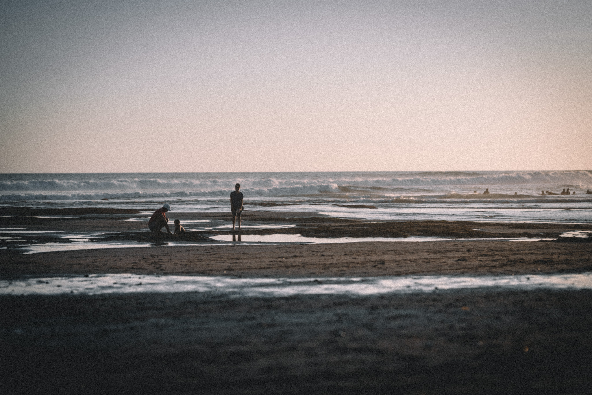 People exploring tidal pools on a quiet Bali beach