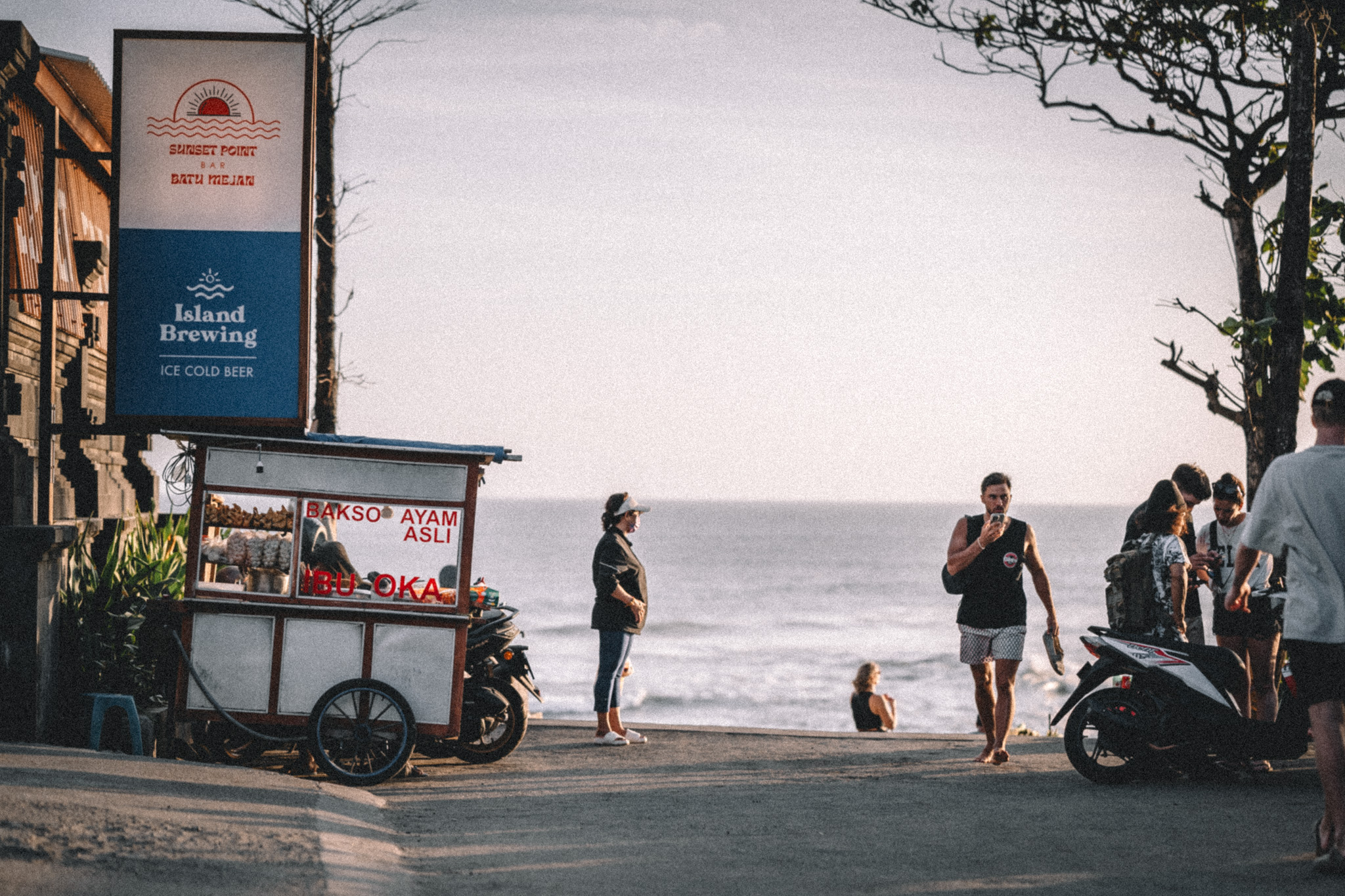A street food cart and people beside the sea at Batu Mejan, Bali