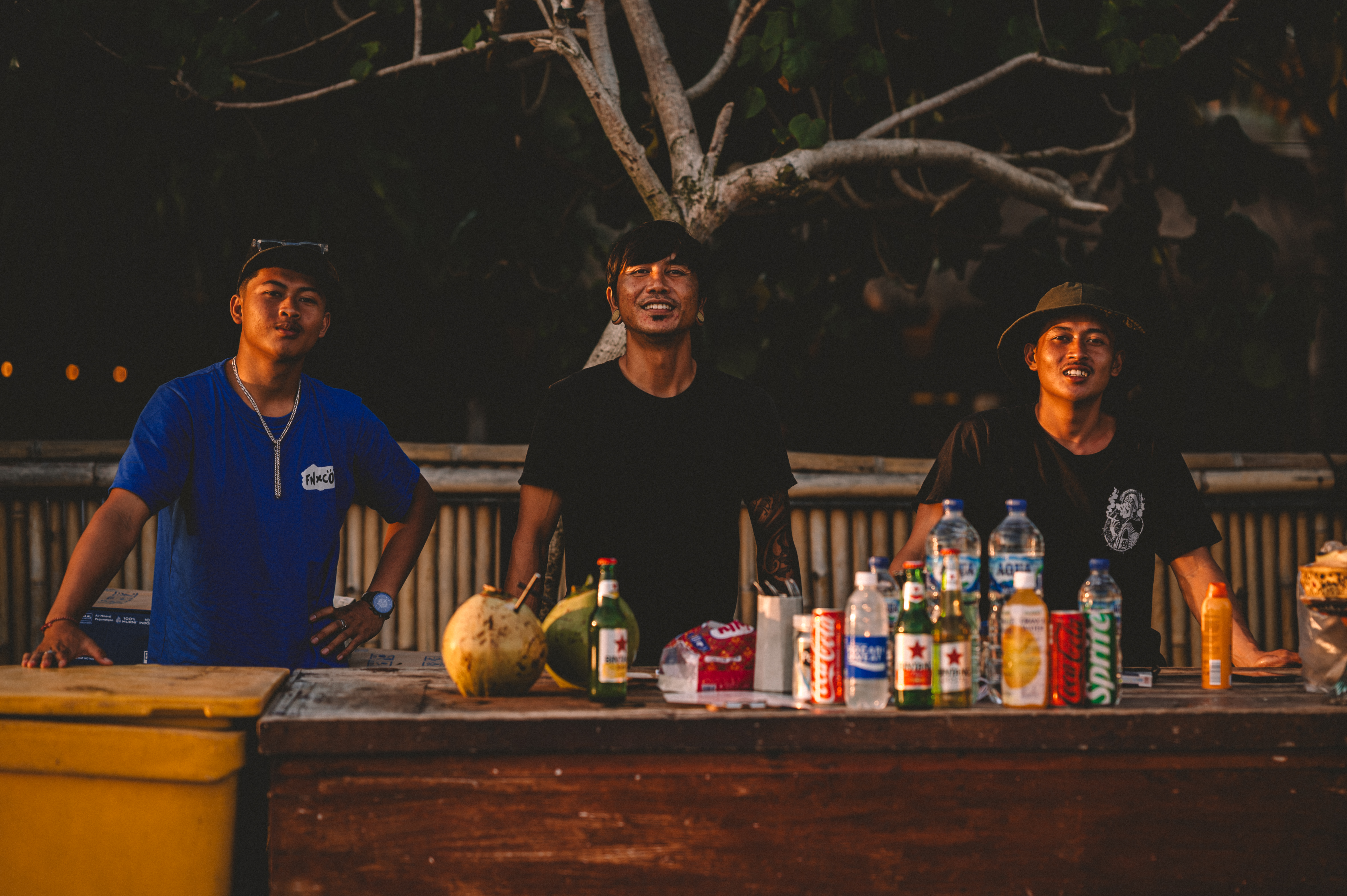 Three men behind a beach bar in warm evening light in Bali