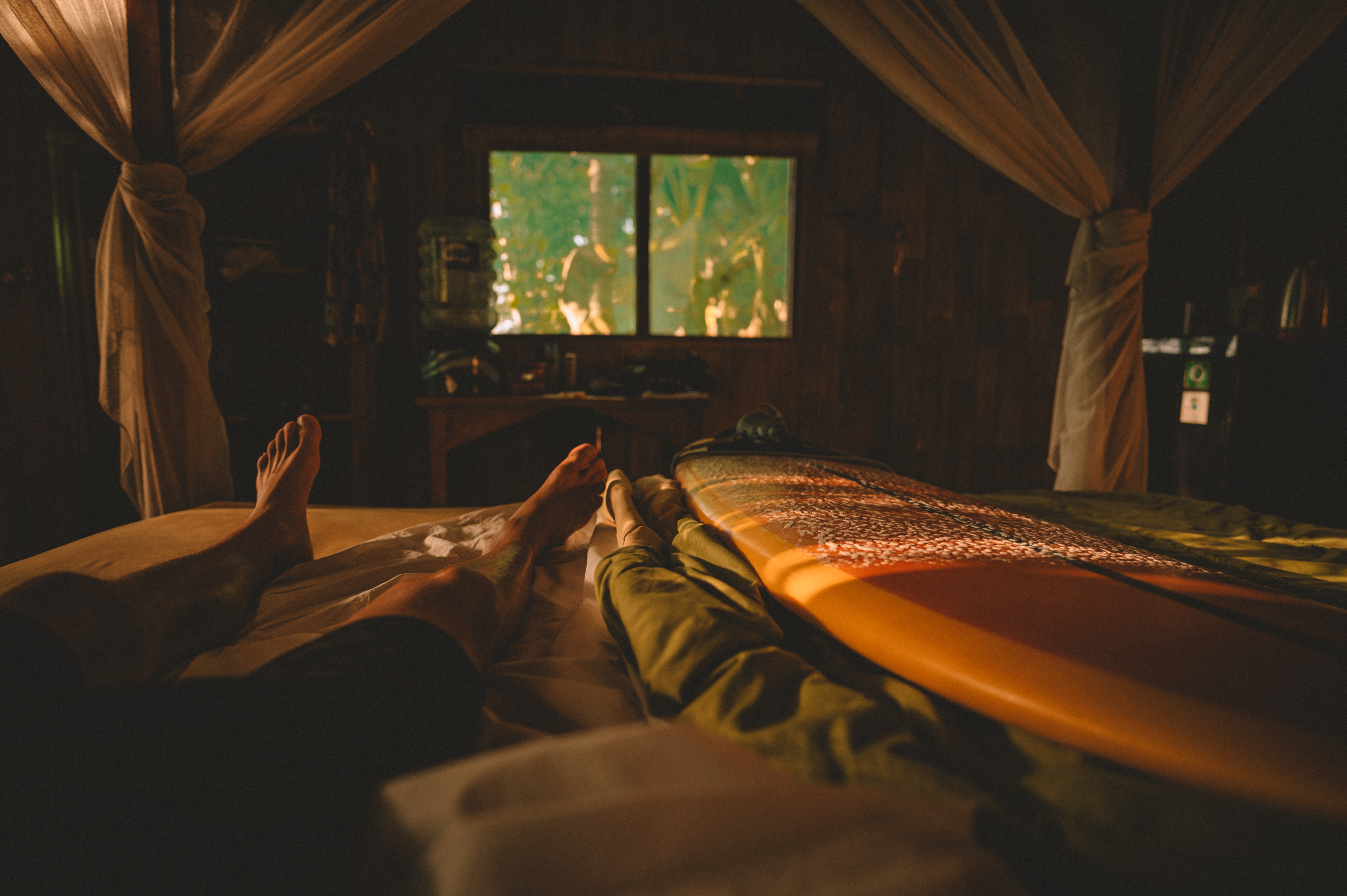 Resting beside a surfboard in a warmly lit room in Bali