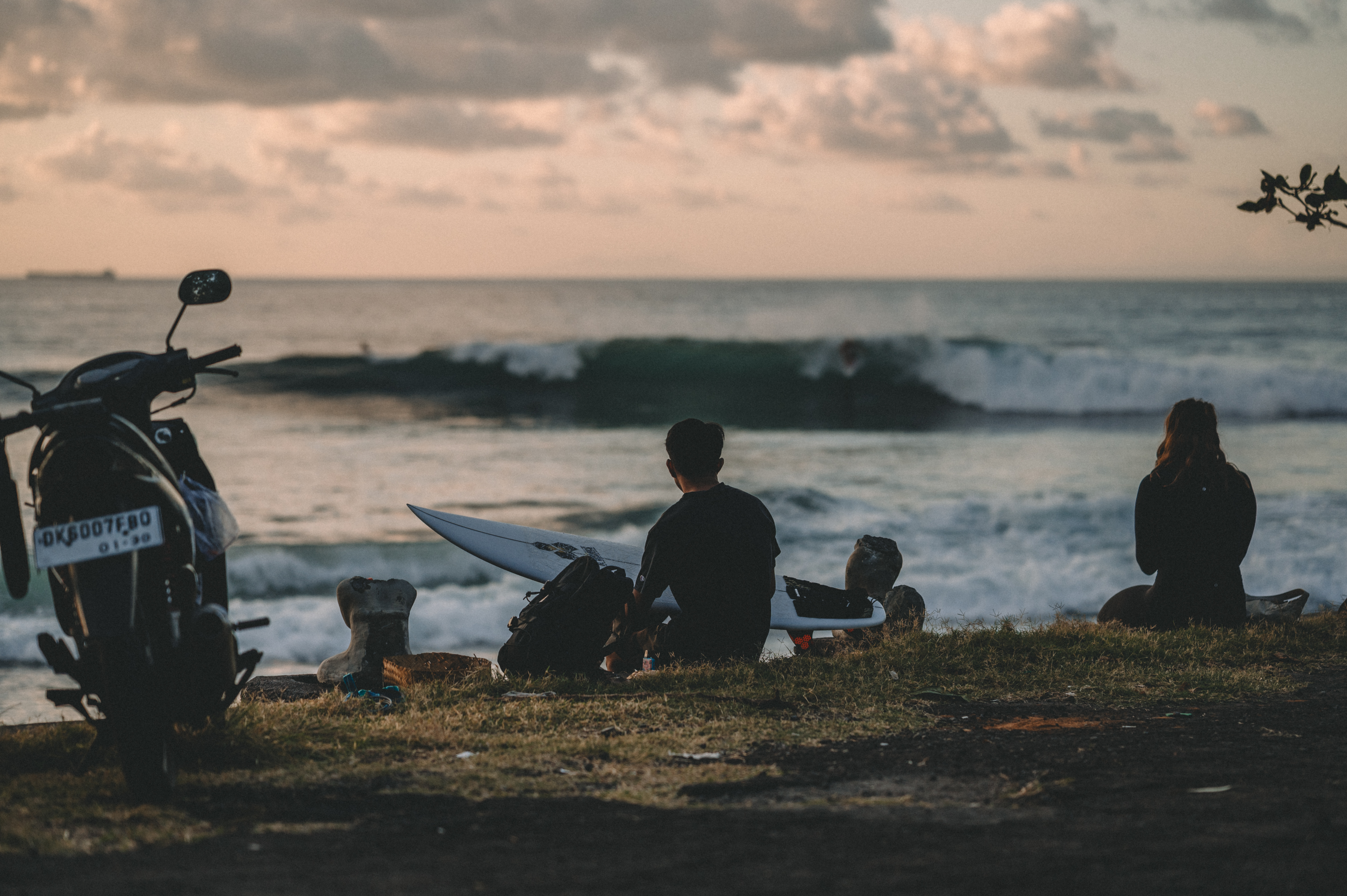People resting with surfboards and watching the waves in Bali