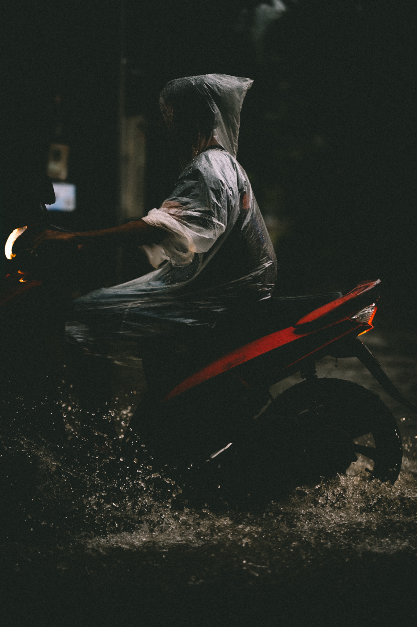 A scooter rider in a transparent rain poncho