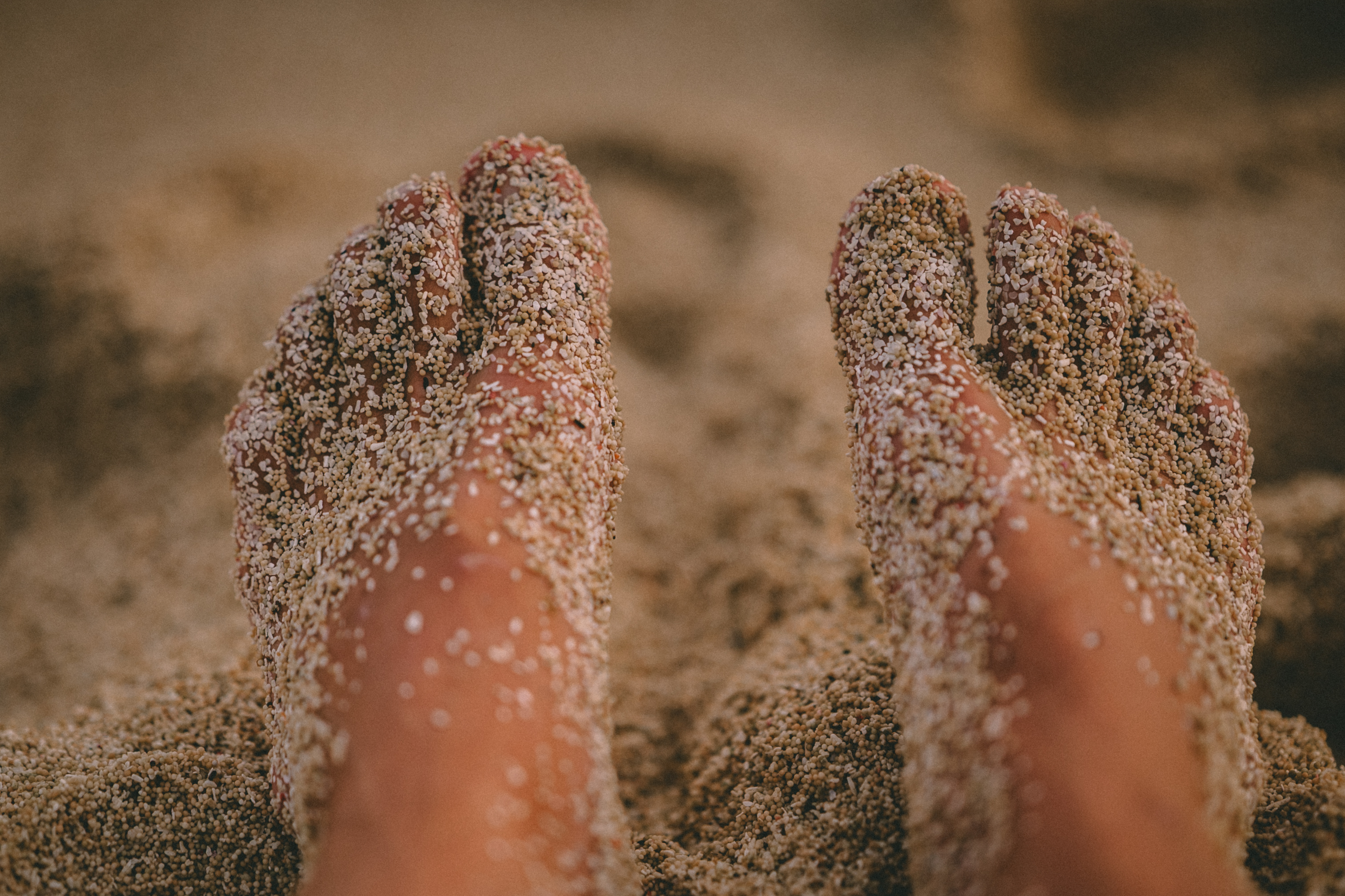 Bare feet covered in coarse sand on a Lombok beach